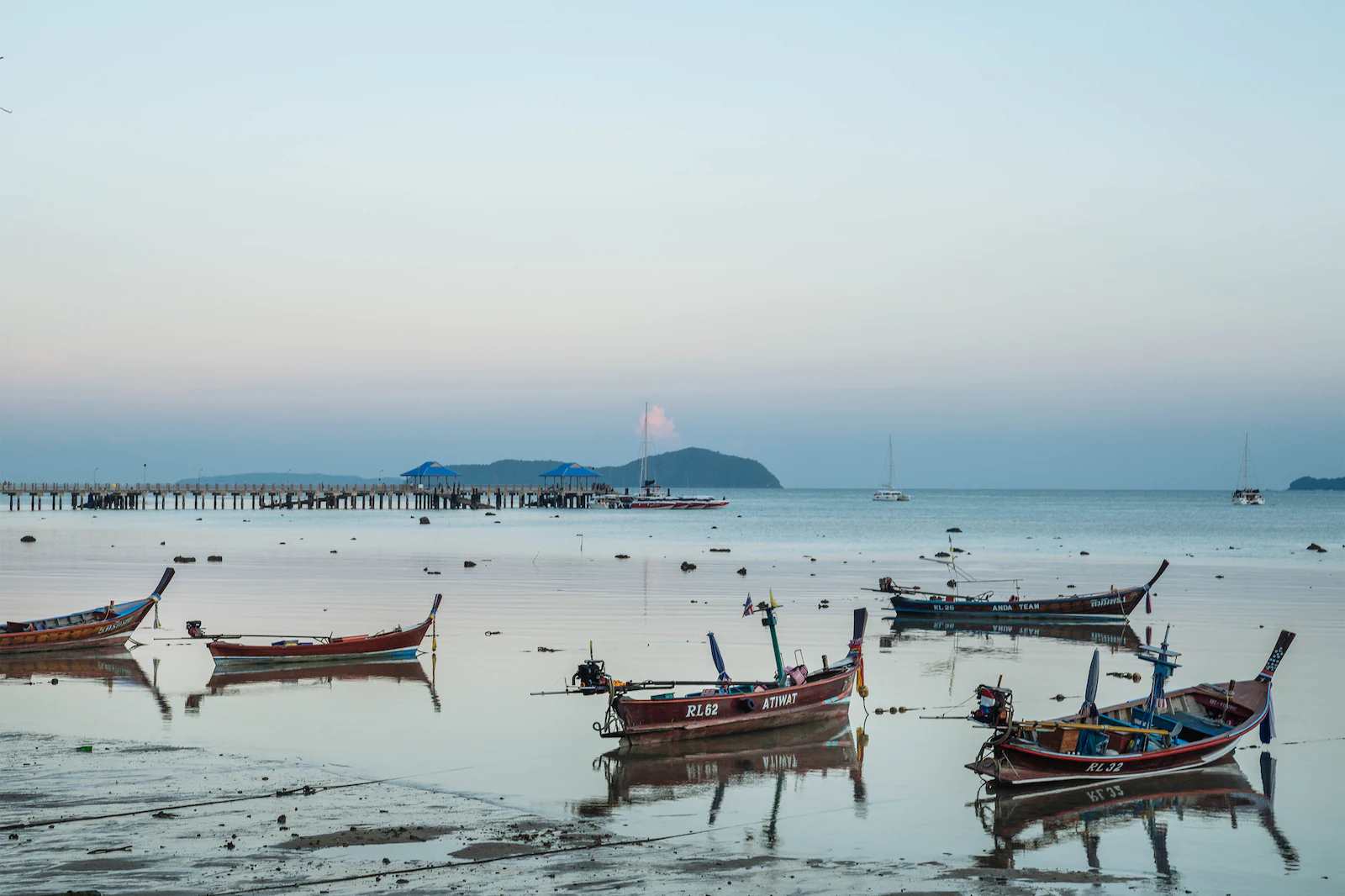 Multiple Sampan boats resting by Phuket sea with island in distance